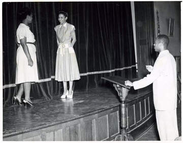 African-American students on a stage with an African-American teacher directing them.