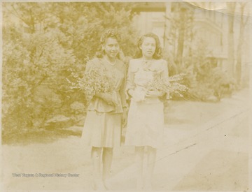 Two female African-American students hold flowers.