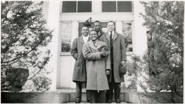 Four male Storer students pose for a portrait on the steps of a building.