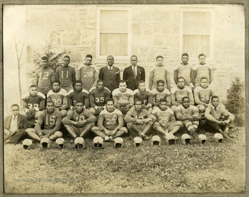 Storer College football team in uniform by building.