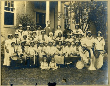 Storer College band members in uniform with instruments in front of building. Pres. &amp; Mrs. McDonald in back row.