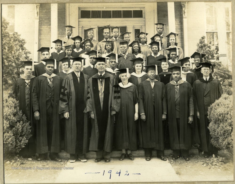 Group photo of Storer College, class of 1942, standing in caps and gowns on front steps of building on campus. Pres. and Mrs. McDonald in middle of bottom row.