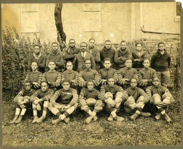 Storer college football team in uniform by building.